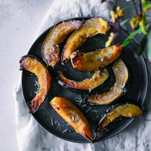 roasted acorn squash pieces on a dark plate with a white napkin