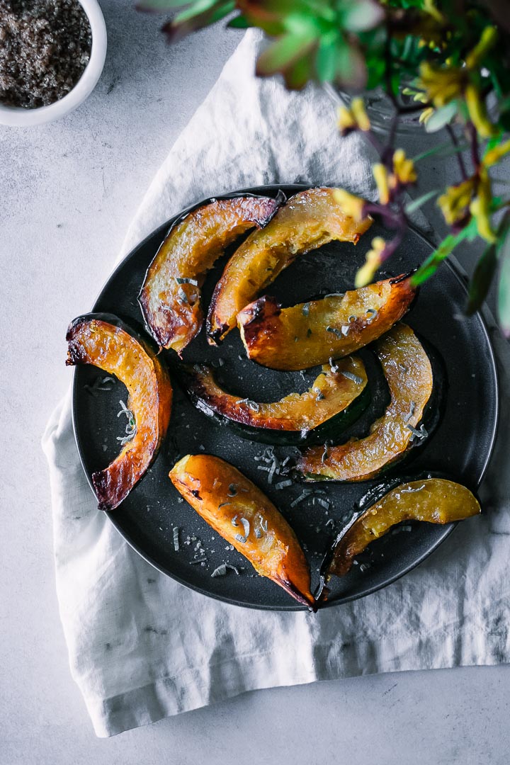 roasted acorn squash pieces on a dark plate with a white napkin