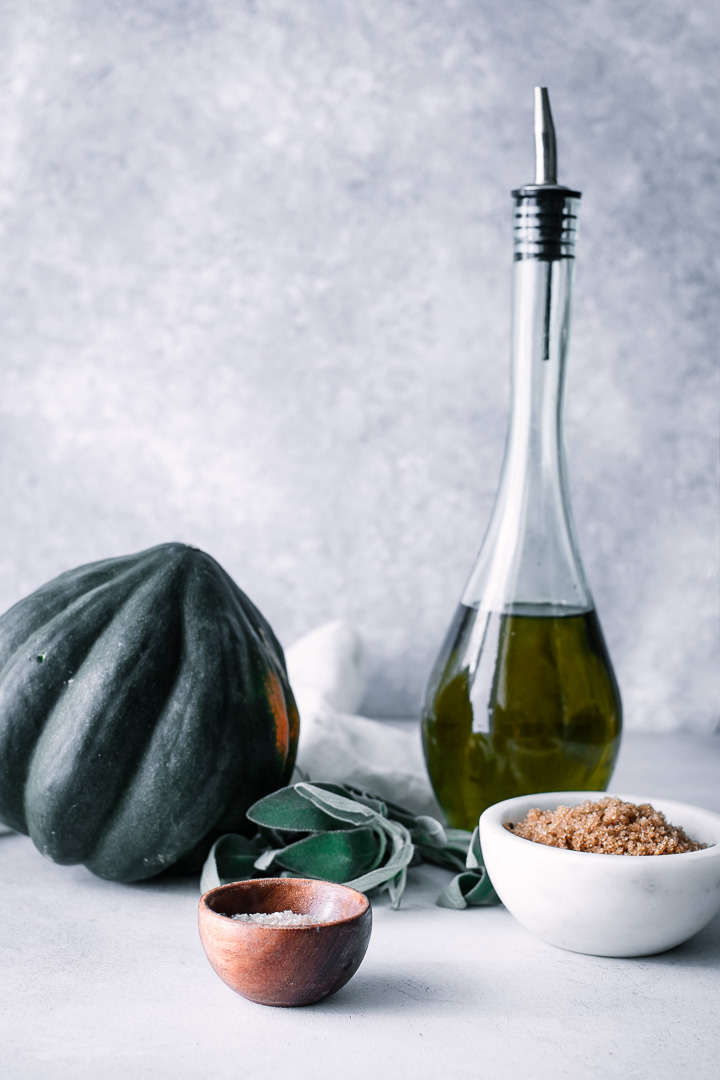 acorn squash, salt, brown sugar, and sage on a blue table