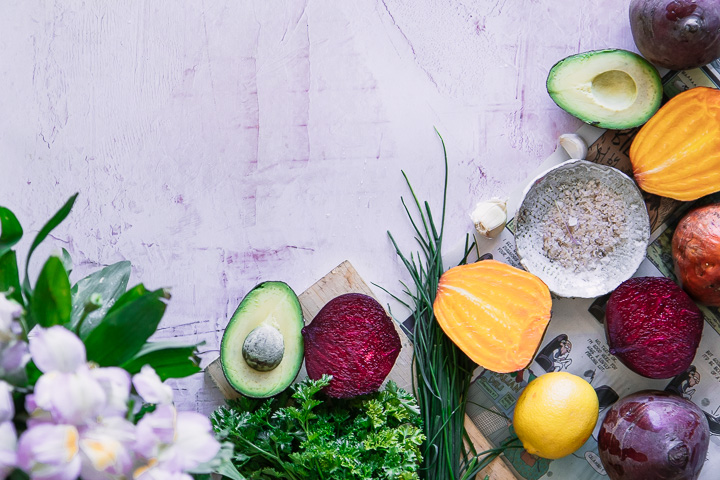 Beets, avocados, lemons, and herbs on a pink table