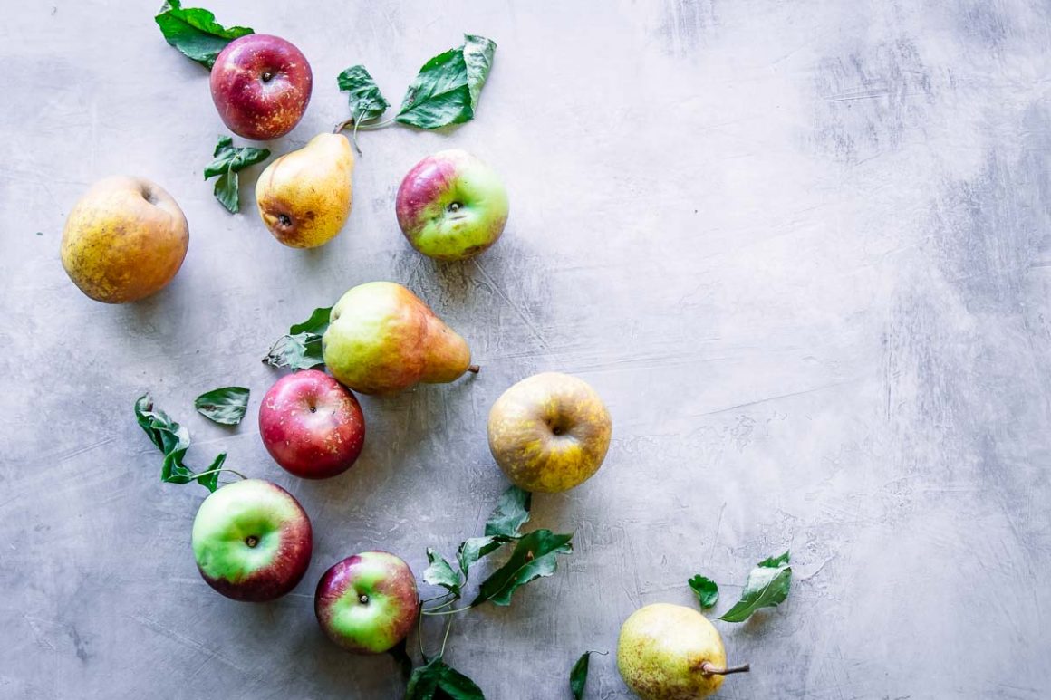 assorted green, red, and yellow apples on a blue-grey table