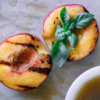 grilled peach halves on a table with drizzled sauce