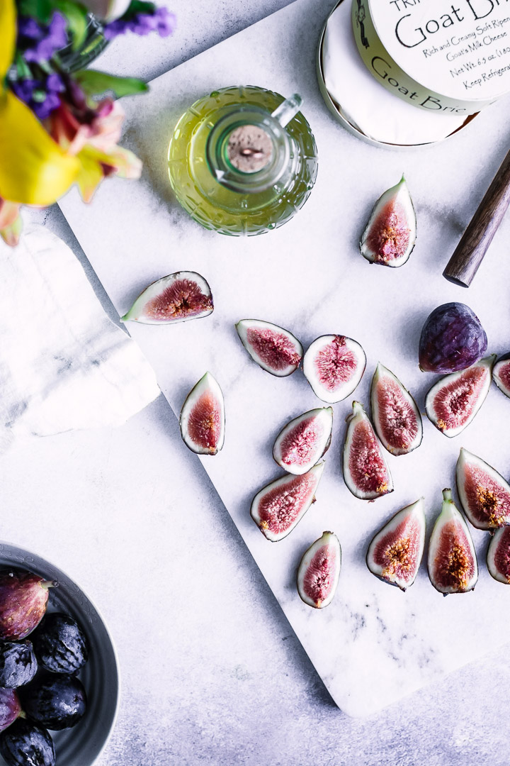 Sliced figs on a cutting board with a bottle of maple syrup.