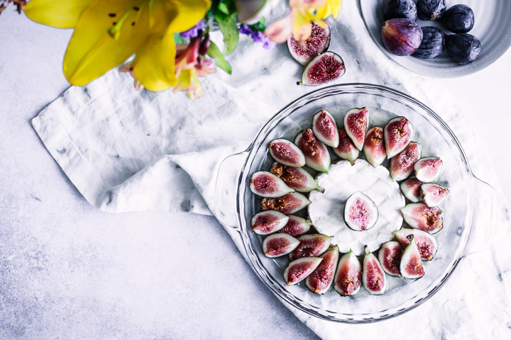 A baking dish with brie and figs with yellow flowers.