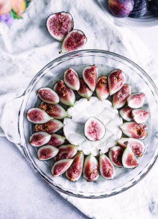 A glass baking dish with figs, brie, and maple syrup.