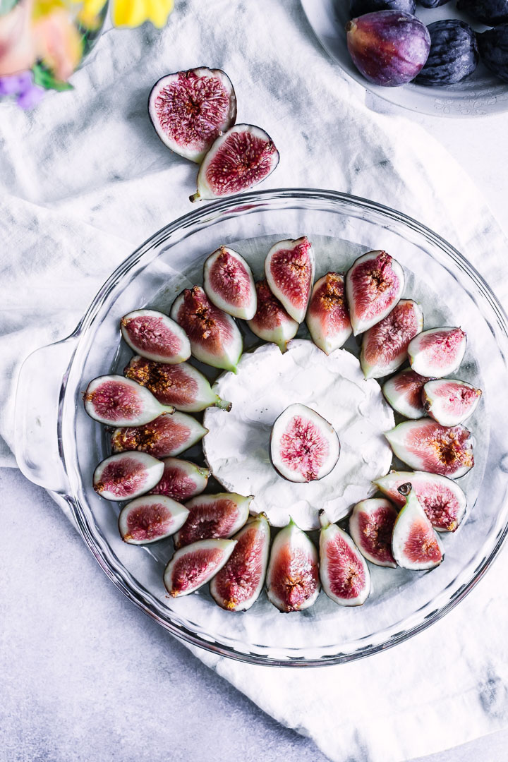 A glass baking dish with figs, brie, and maple syrup.