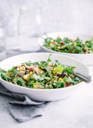 A farro and arugula salad in two bowls on a white table.
