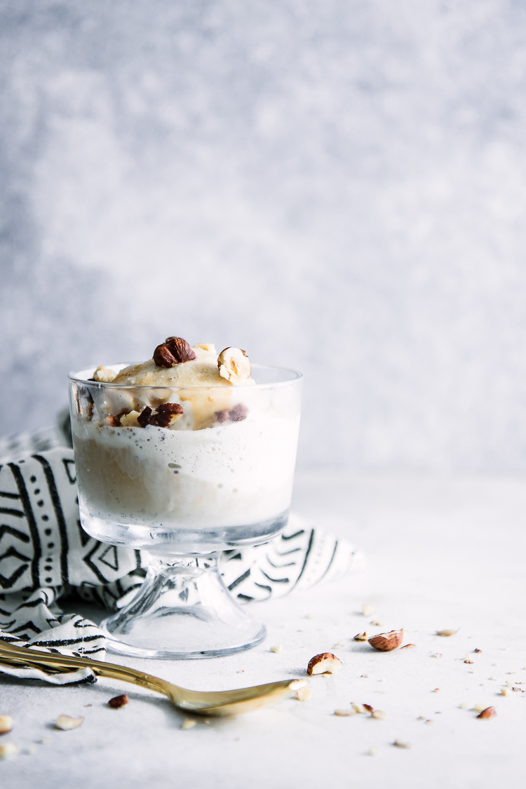 A glass dessert dish with affogato, made with gelato, espresso, and hazelnuts.