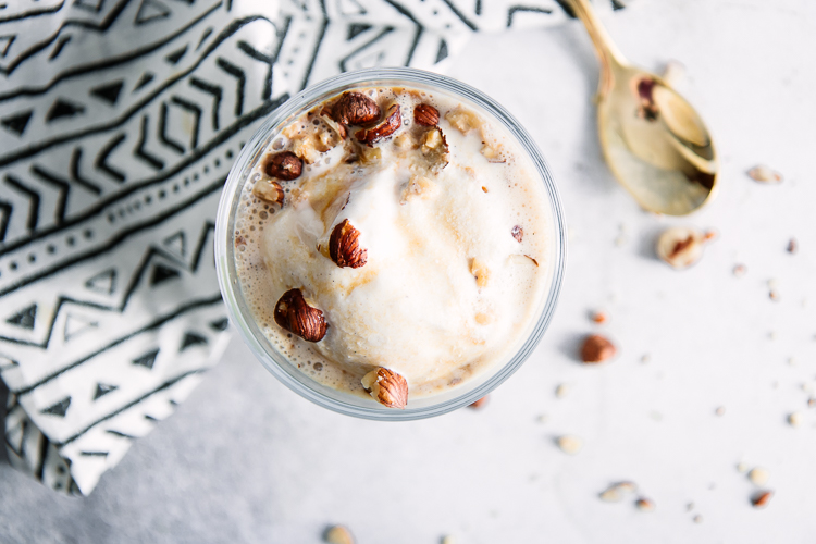 A glass bowl of vanilla gelato with espresso and hazelnuts.