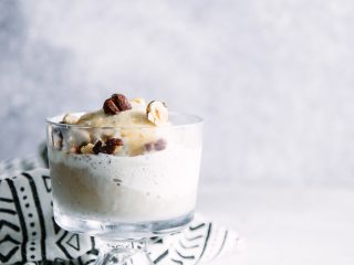 A glass bowl of vanilla gelato with espresso and hazelnuts.