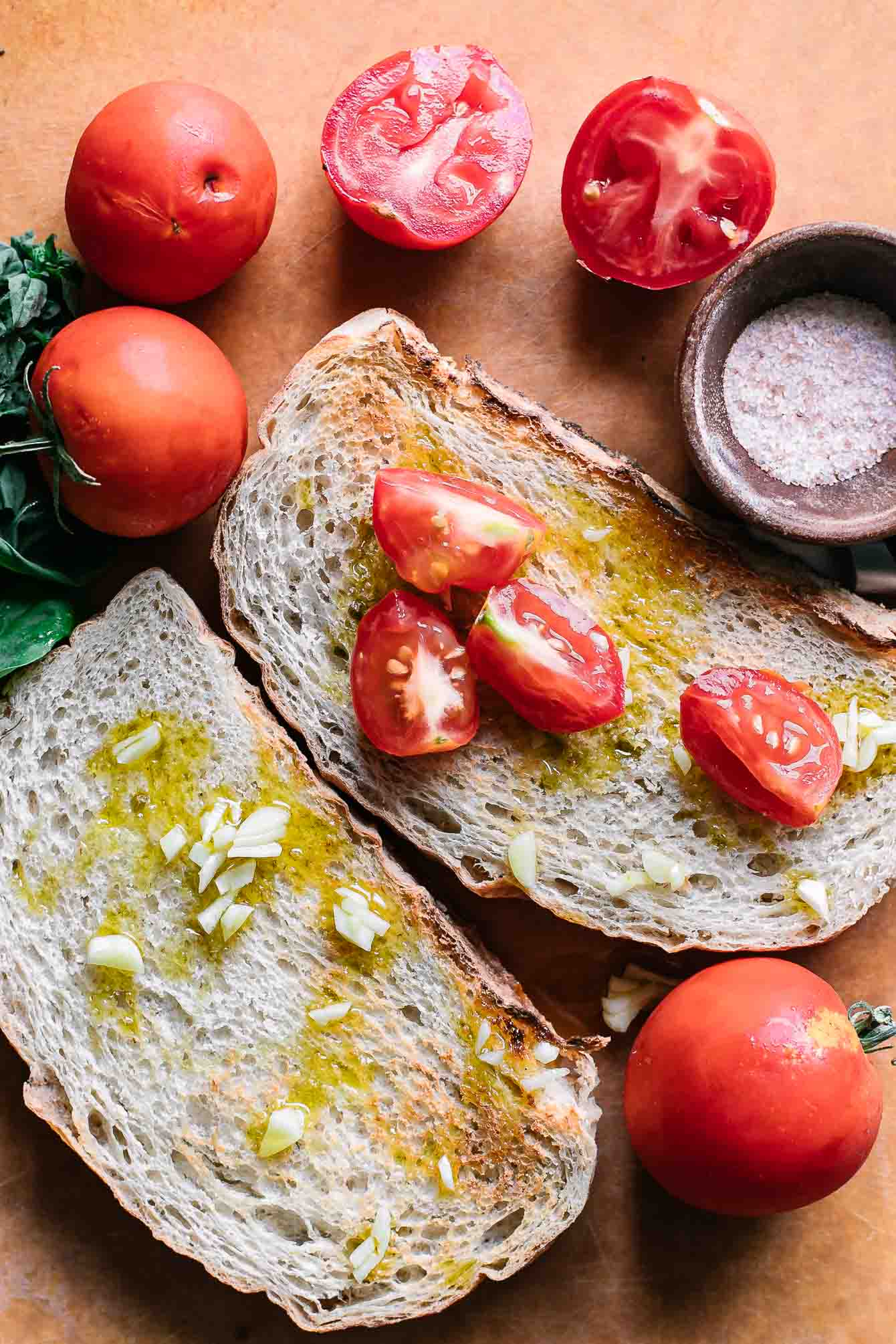 Sliced tomatoes on toasted ciabatta bread on a wood cutting board