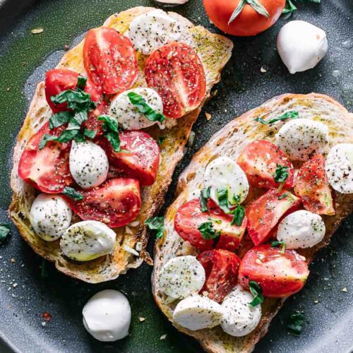 caprese salad on ciabatta toast on a blue plate on a white table