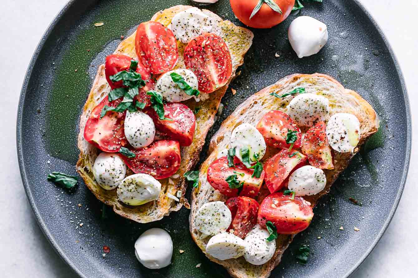 caprese salad on ciabatta toast on a blue plate on a white table