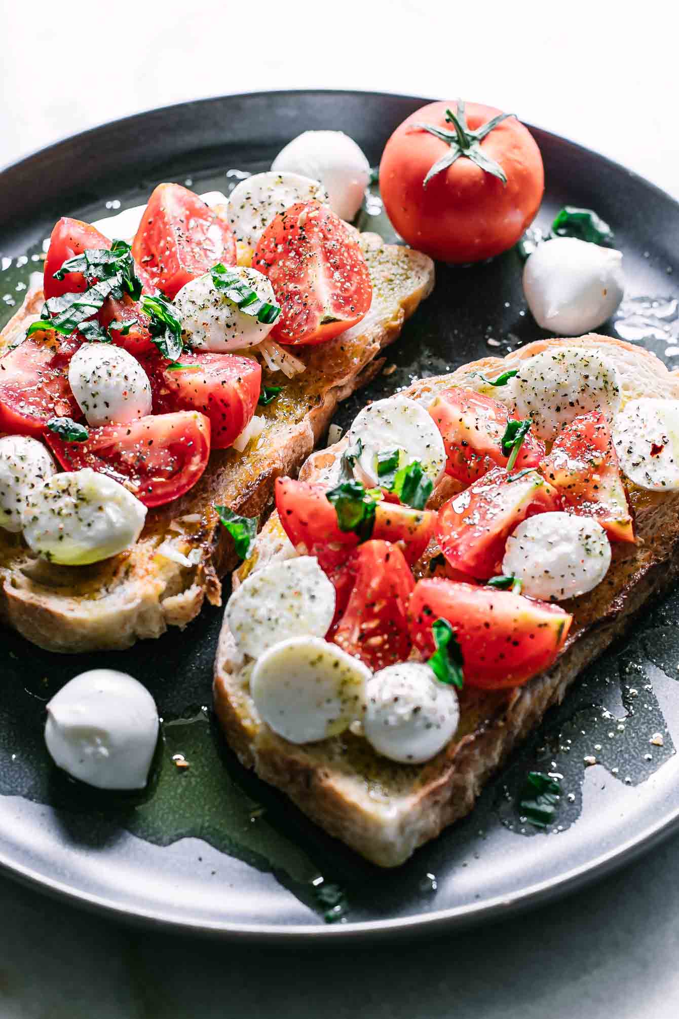 sliced mozzarella, tomatoes, and basil on toast on a plate