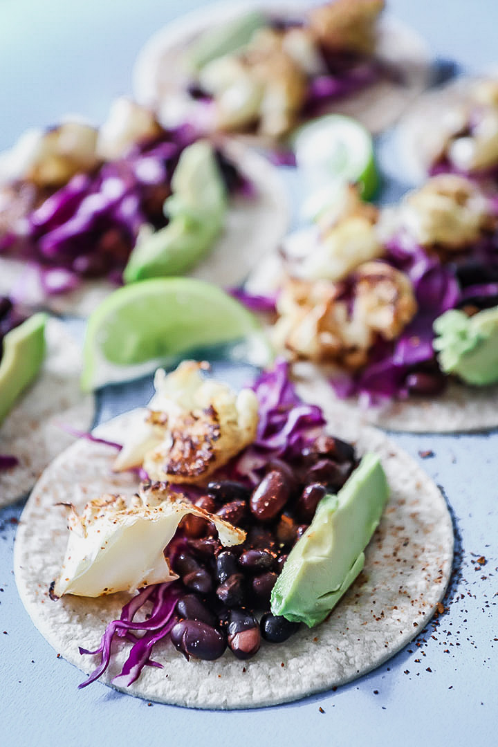 Chli lime cauliflower tacos on a blue table.