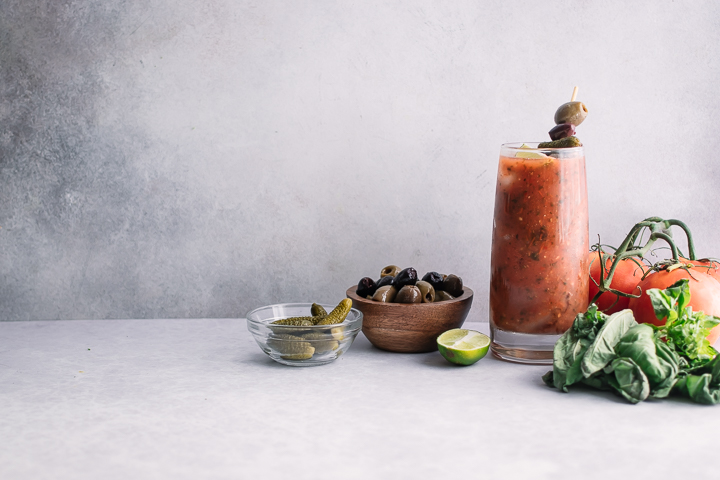 A homemade bloody mary in a tall cocktail glass on a white table.