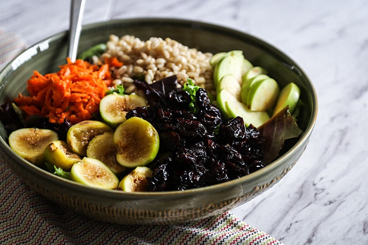 a bowl of warm grains and fall produce on a white table