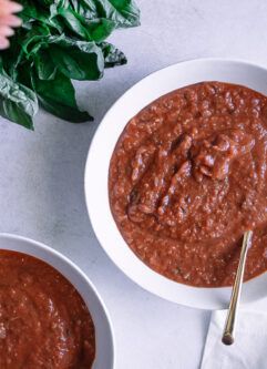A bowl of tomato leek soup on a white and blue napkin.