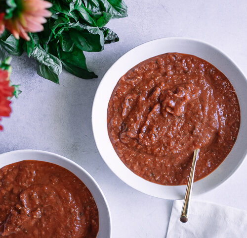 A bowl of tomato leek soup on a white and blue napkin.