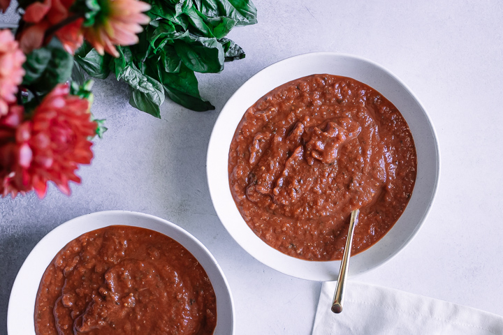 A bowl of tomato leek soup on a white and blue napkin.