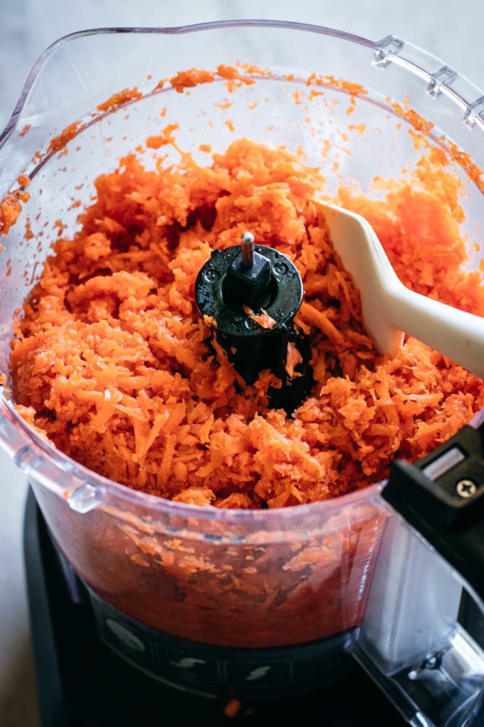 Shredded carrots and a spoon in a food processor