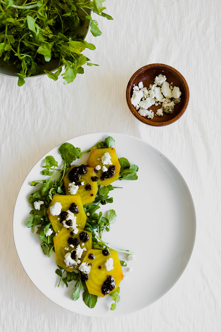 roasted golden beet carpaccio on a white place with a white table.