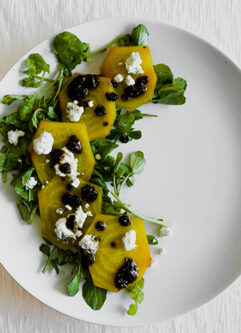 roasted golden beet carpaccio on a white place with a white table.