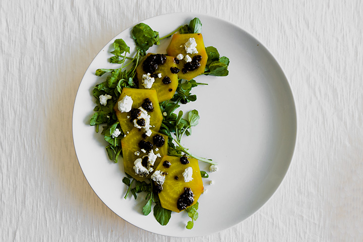 roasted golden beet carpaccio on a white place with a white table.