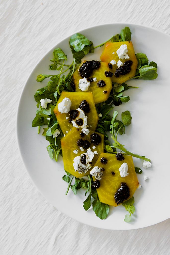 roasted golden beet carpaccio on a white place with a white table.