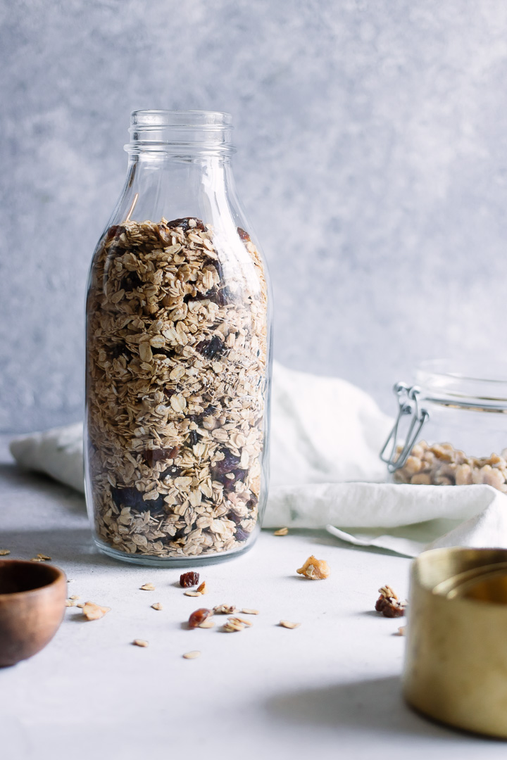 A large mason jar with toasted granola on a white table.