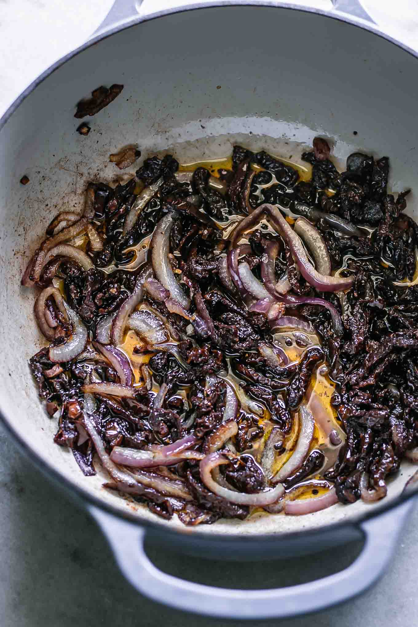 a pot with caramelized onions and sun-dried tomatoes on a white table