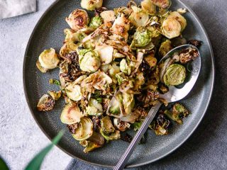 A blue plate with roasted brussels sprouts and the words "maple mustard brussels sprouts" in black writing