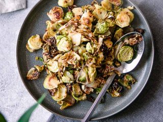 A blue plate with roasted brussels sprouts and the words "maple mustard brussels sprouts" in black writing