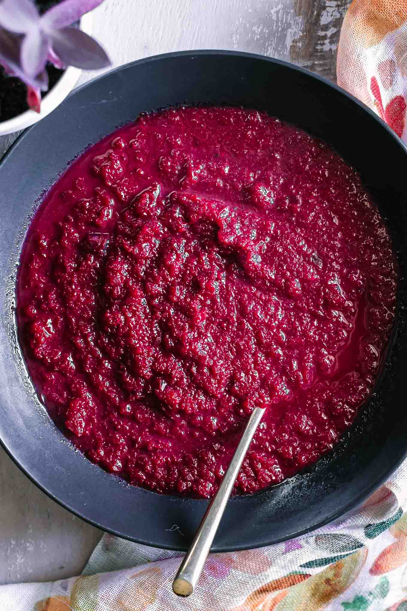 a roasted red beet and apple soup in a black bowl with a gold fork