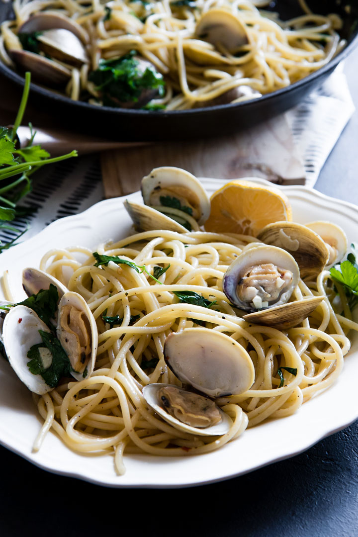 bucatini with clams, white wine, and parsley on a black table