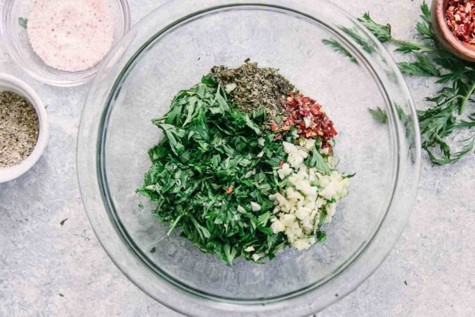 carrot greens, garlic, red pepper, and spices in a glass bowl