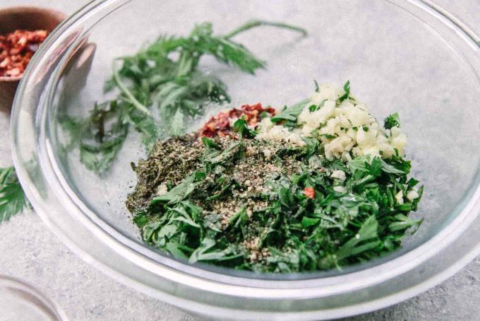 carrot greens, garlic, red pepper, and salt and pepper in a small glass bowl