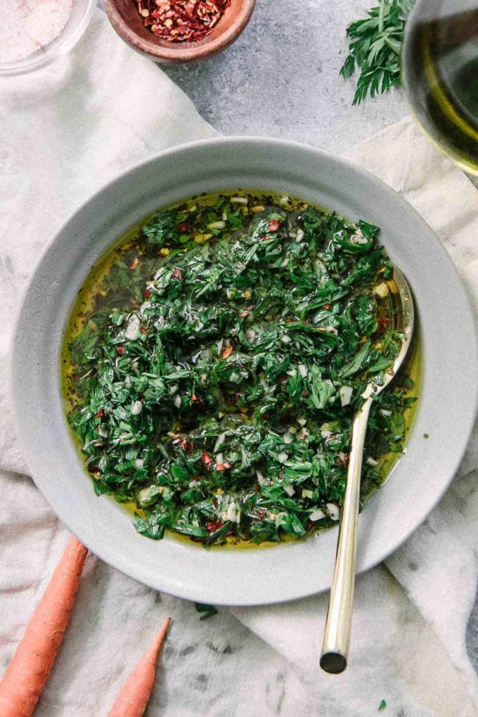 a blue bowl filled with chimichurri sauce and a gold spoon