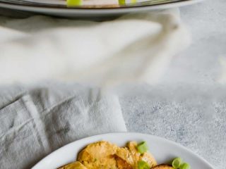 stacked healthy baked patacones smashed plantains on a white plate with green mojo sauce