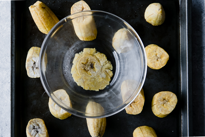 smashed healthy baked plantain patacones on a black cookie sheet