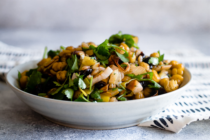 A bowl of za'atar crispy chickpea and leek salad on a blue table.