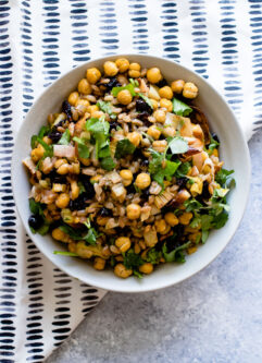 za'atar crispy chickpea and leek salad in a white bowl on a blue table with a white napkin