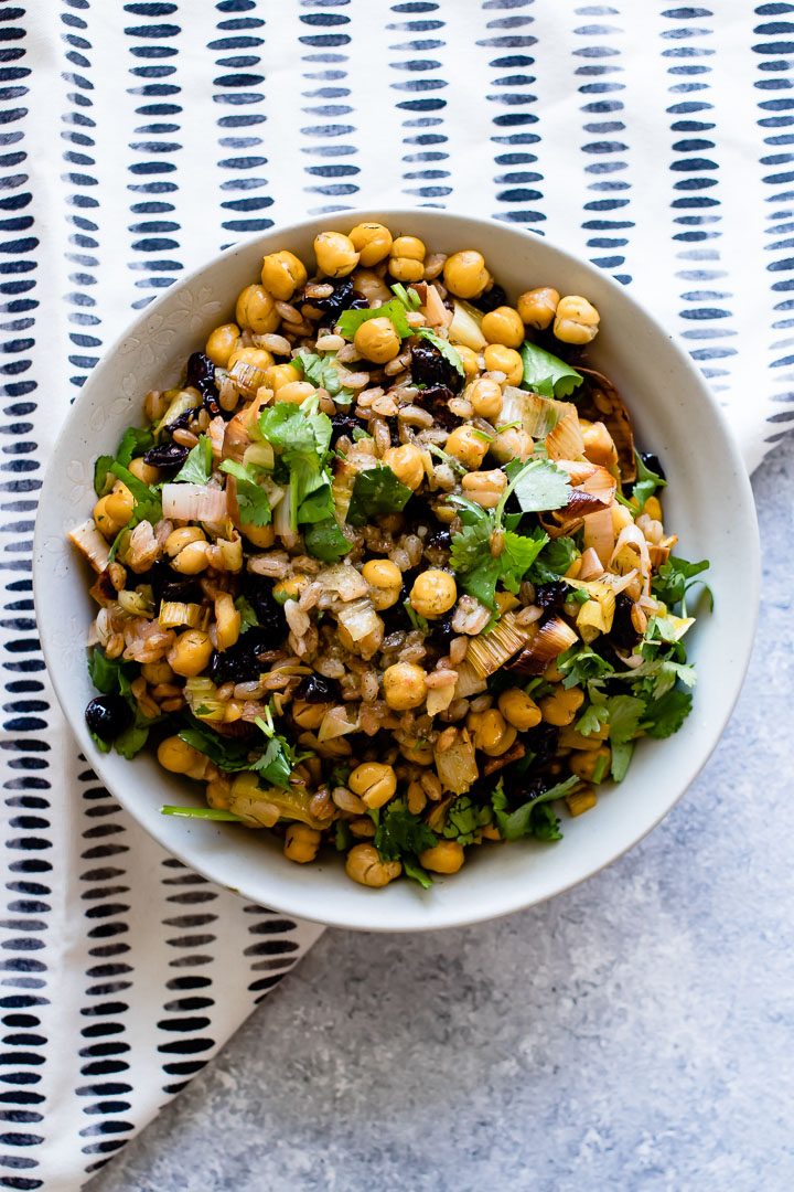 za'atar crispy chickpea and leek salad in a white bowl on a blue table with a white napkin