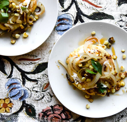 Colombian spicy vegetable recipe on a white plate with spicy roasted vegetables on a colorful patterned background.