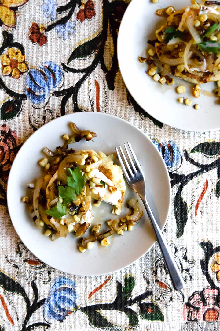 Colombian spicy vegetable arepas recipe on a white plate with spicy roasted vegetables on a colorful patterned background.