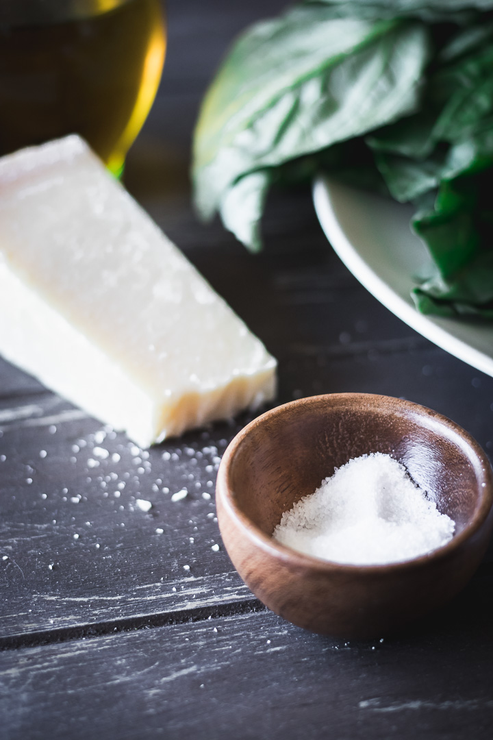 A bowl of salt and a block of parmesan cheese on a wood table
