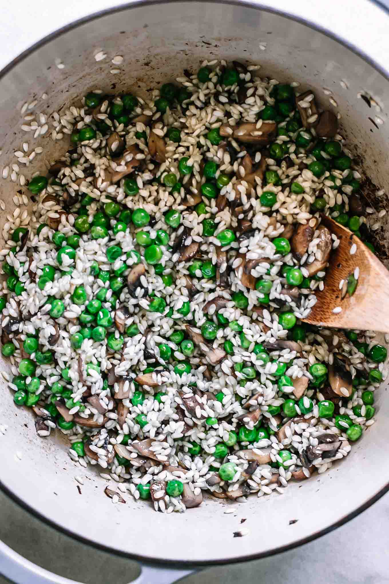 risotto rice, mushrooms, truffles, and peas in a large pot