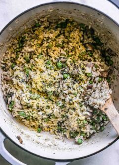 a Dutch oven with mushroom and truffle risotto and a wooden spoon a white table