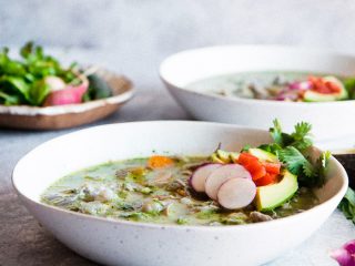 two white bowls of pozole verde chicken soup on a blue table