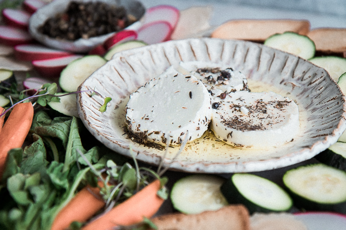 A white plate with feta cheese and assorted raw vegetables on a platter.